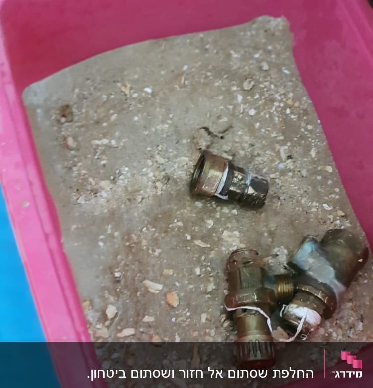 חלקי מתכת בתוך מיכל ורוד עם חול